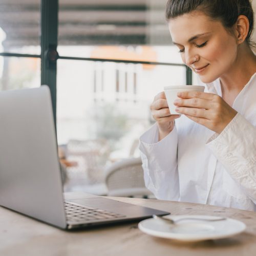young-woman-drinking-coffee-working-online-using-h-2024-11-27-13-29-39-utc-min